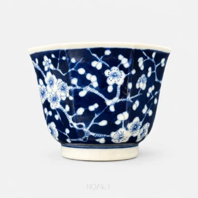 Every face of the body carries the same plum tree, white blossom picked out of a solid blue ground and running from one panel into the next.