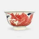 A five-clawed dragon in underglaze red sweeps across the body of this Ya Shou cup, its head thrown back mid-turn through cobalt clouds.