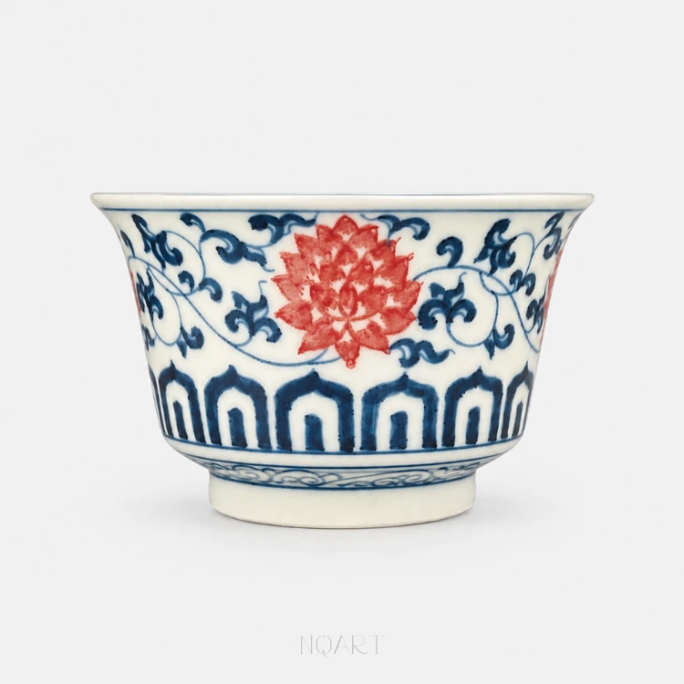 Up close, a single lotus bloom in underglaze red — you can see where the brush went, petal by petal, against the blue scroll behind it.