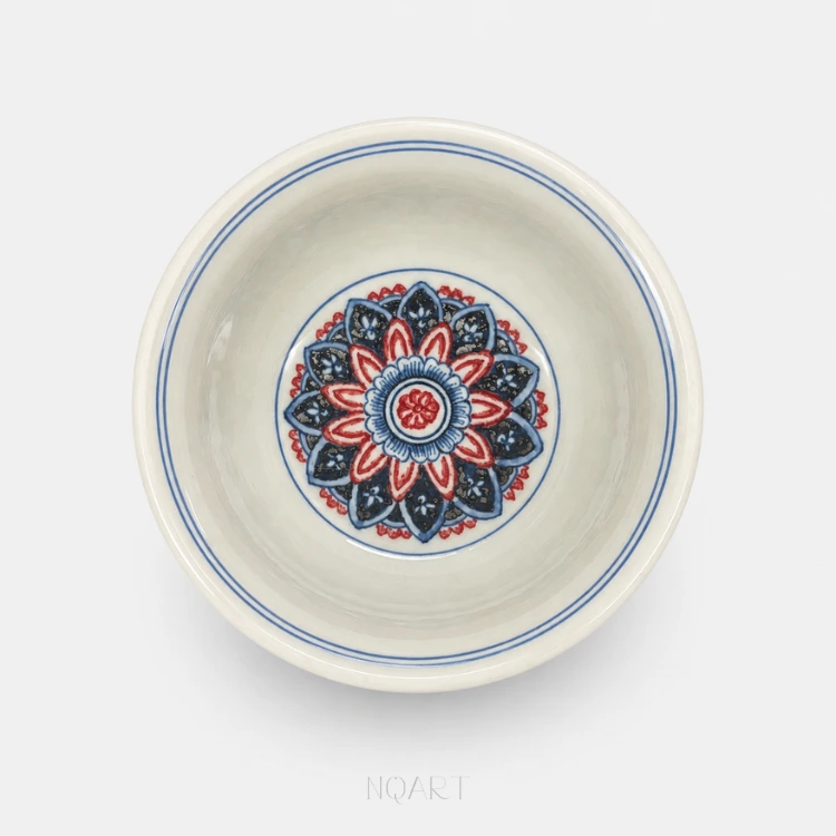 The medallion in the middle is built in rings — blue petals flecked with white, then a run of red — with two plain blue lines just inside the rim.