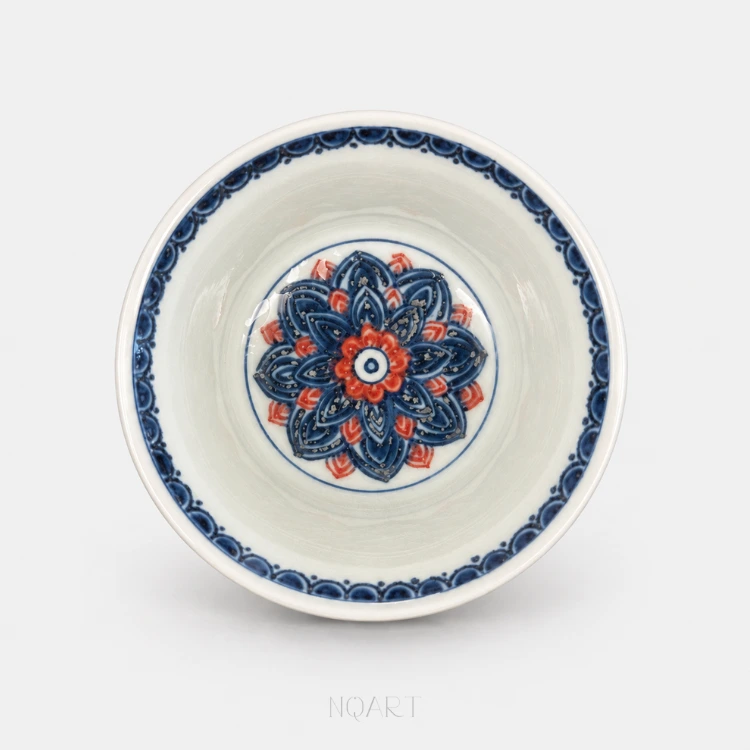 Down inside, the base carries a full lotus medallion — layered blue petals opening from a ring of red — and a repeating border runs just inside the rim.