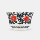 The lotus vine runs unbroken around this horse hoof cup, carrying two blooms in underglaze red through a dense mass of cobalt blue scroll.