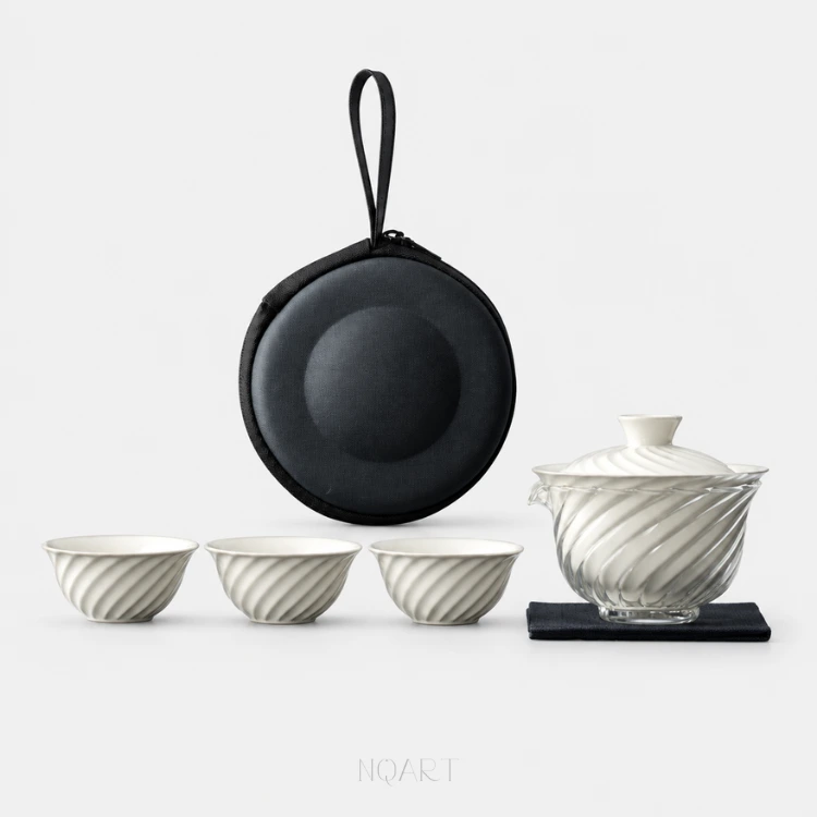 Five pieces on plain white: a camping tea set — three white cups in a row, the glass pitcher with its porcelain lid on top, a black tea cloth, and the round case standing behind them.