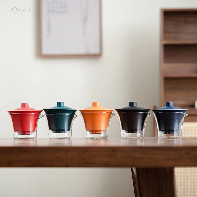 Five finishes of the same compact tea set stand in a row on the table — red, dark green, orange, black and blue.