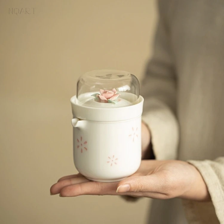 On one palm, the whole gongfu tea set gift stands assembled — lid on, rose up, and the glass cup turned over on top of it.