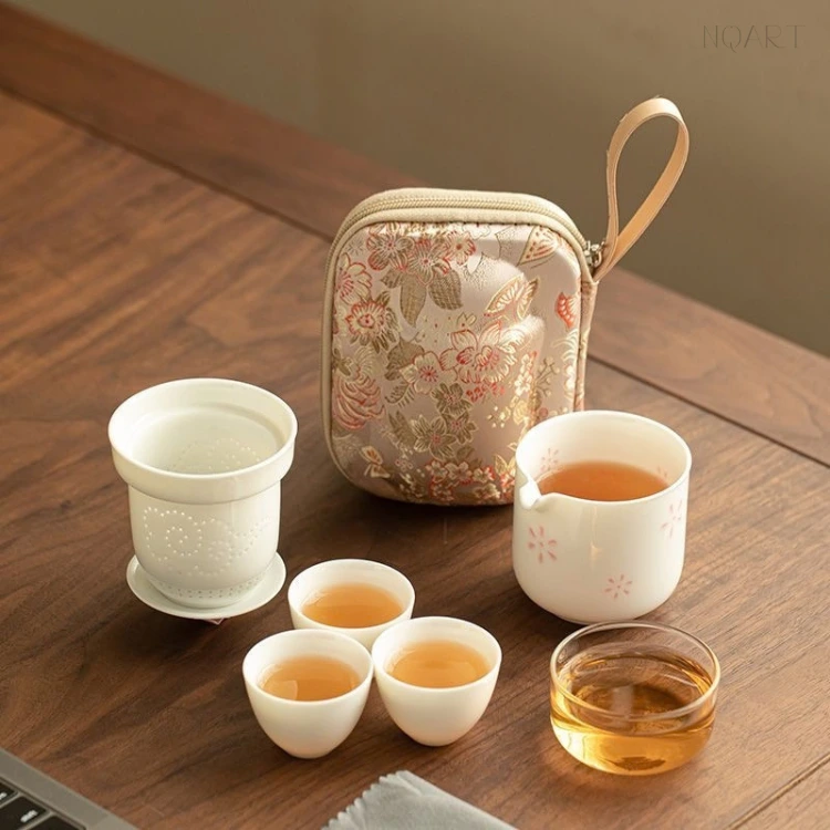 Laid out on the table, this outdoor tea set covers one straight line: the strainer on its dish, the brewing cup, three cups and the glass, with the case behind.