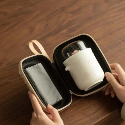 With the padded case open, one half holds the folded tea towel and the other the brewing cup under its glass cover.
