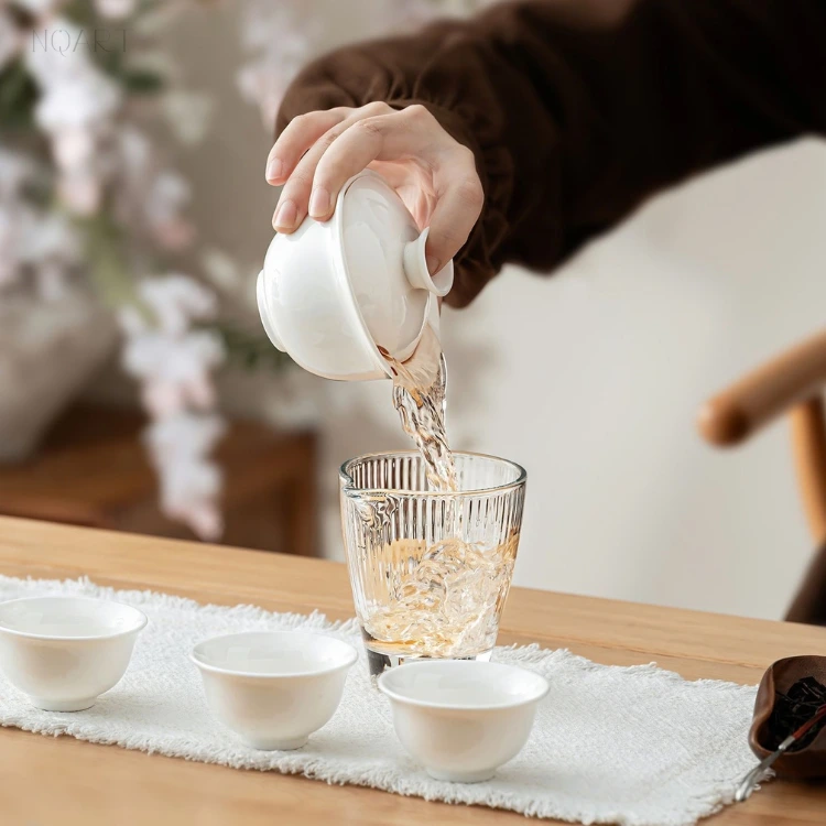 Plain white throughout — in this complete tea set the gaiwan tips into the glass fairness pitcher, nothing on the pieces breaking the glaze.