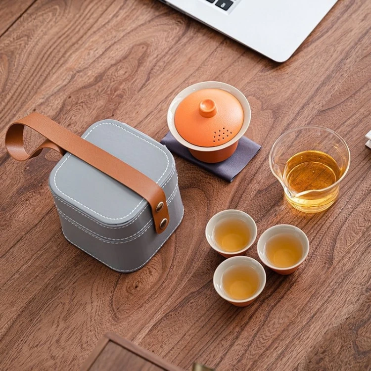 Looking straight down, the portable tea set with bag lies flat on the table — case, gaiwan, three cups and the glass pitcher, all in one frame.
