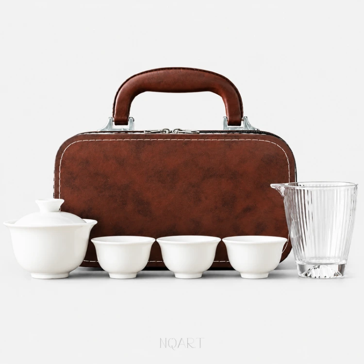 A six-piece portable tea set with carrying case, laid out in a row: porcelain gaiwan, three tea cups and a glass fairness pitcher, with the brown case standing behind them.