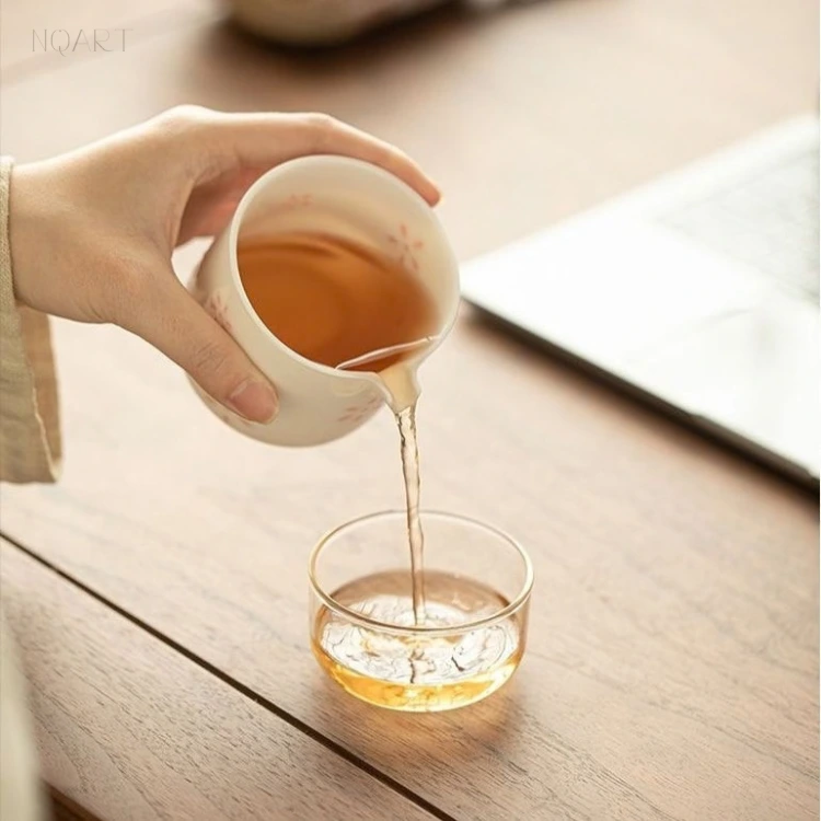 The spout sends a thin stream down into the glass tea cup — clear enough to watch the colour land before the cup is anywhere near full.