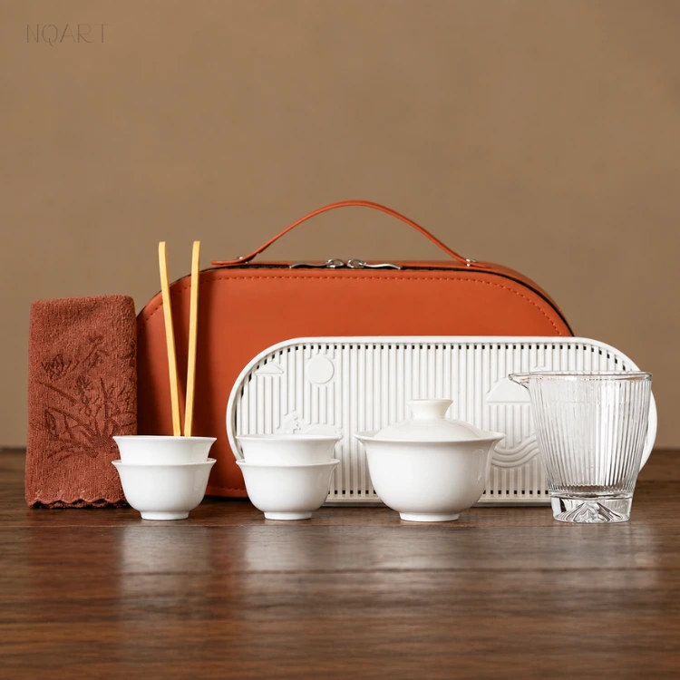 Set out on wood, a tea gift set in the orange colourway — the slotted white tea tray, the rust-coloured tea towel and the case standing behind them.