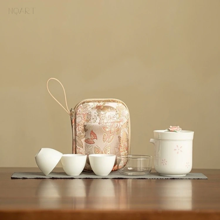A gift for tea lovers who travel: the floral case, the rose-topped brewing cup and the stacked cups standing in one line across the wood.