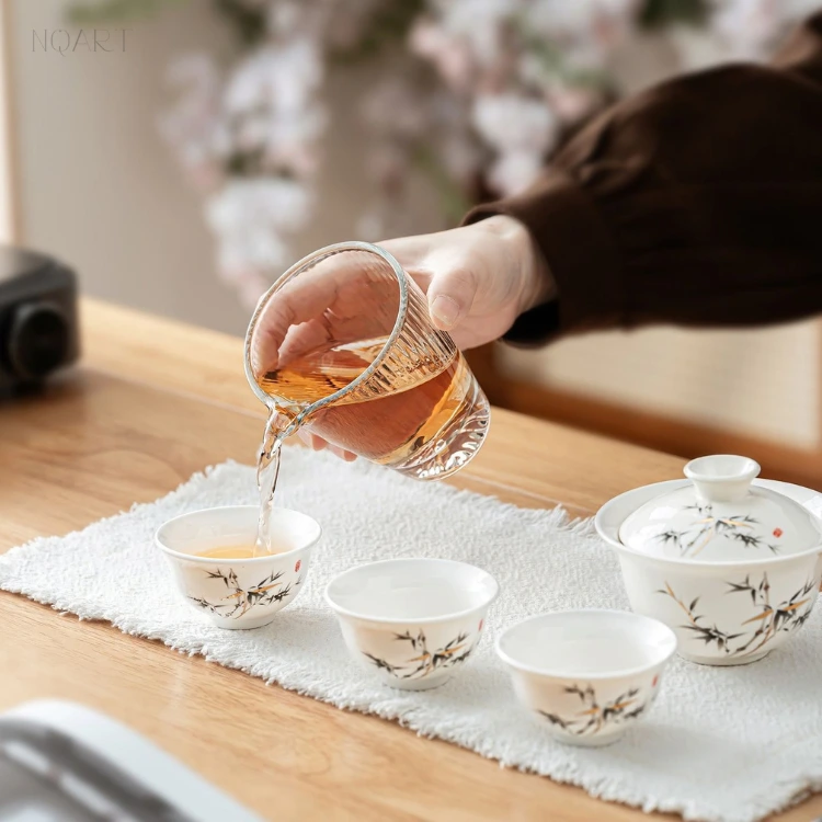 Mid-service in the lucky bamboo gongfu tea set, the glass fairness pitcher tipping tea into one of the cups.