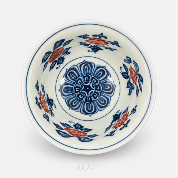 Down at the bottom of the bowl, a blue medallion closes its petals in rings, with the vine running round the wall above it.