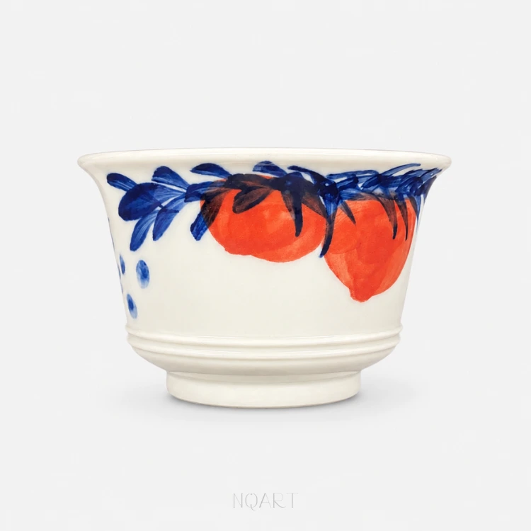 Two persimmons sit side by side in underglaze red, blue leaves laid over them and a scatter of blue berries running off to the left.