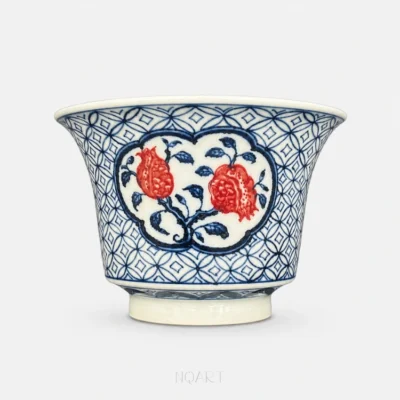 The ground stops at a heavy blue outline and leaves a white panel in the shape of a ruyi head, with two pomegranates and their branch inside it.