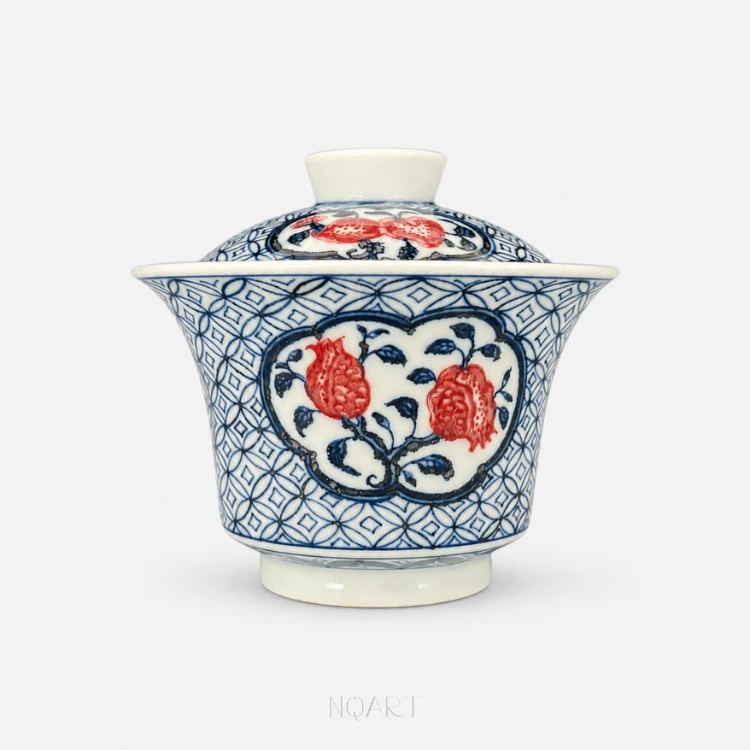 A ground of interlocking coins covers the whole of this gaiwan, bowl and lid alike, broken by cartouches that hold pomegranates in underglaze red.