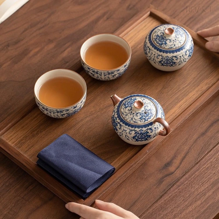 From directly above, the tea pot sits closed with its wood knob and handle, two cups poured and waiting beside it.