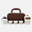 For the product shot, the whole set on white: a tea set with tea caddy — three cups and a brewing cup banded in gold-outlined arches, a lidded tea jar, and the brown case standing behind them.