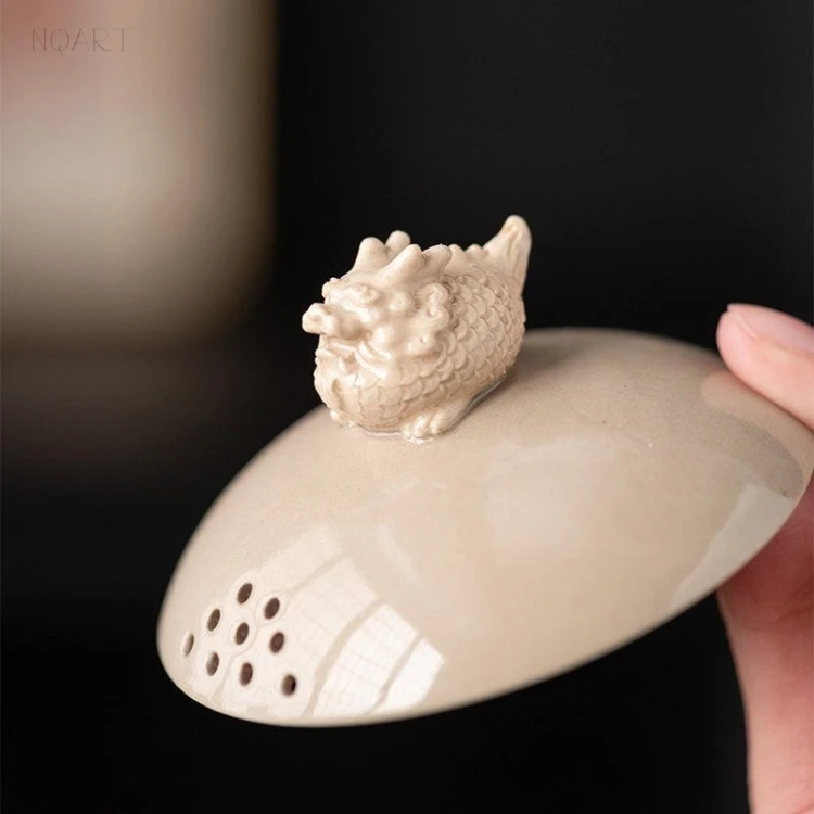 The lid turned to the light: a patch of fine holes near its edge, and a sculpted knob in the same glaze on top.